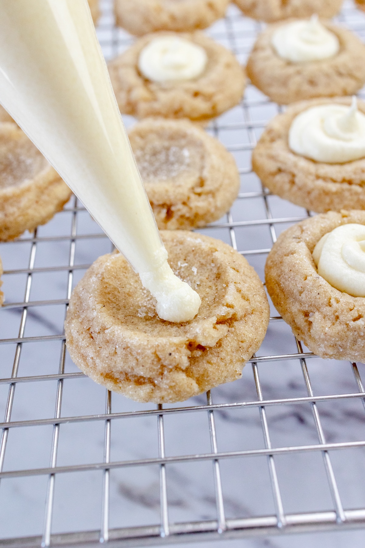 Close up of thumbprint cookies being piped full of Eggnog Filling.