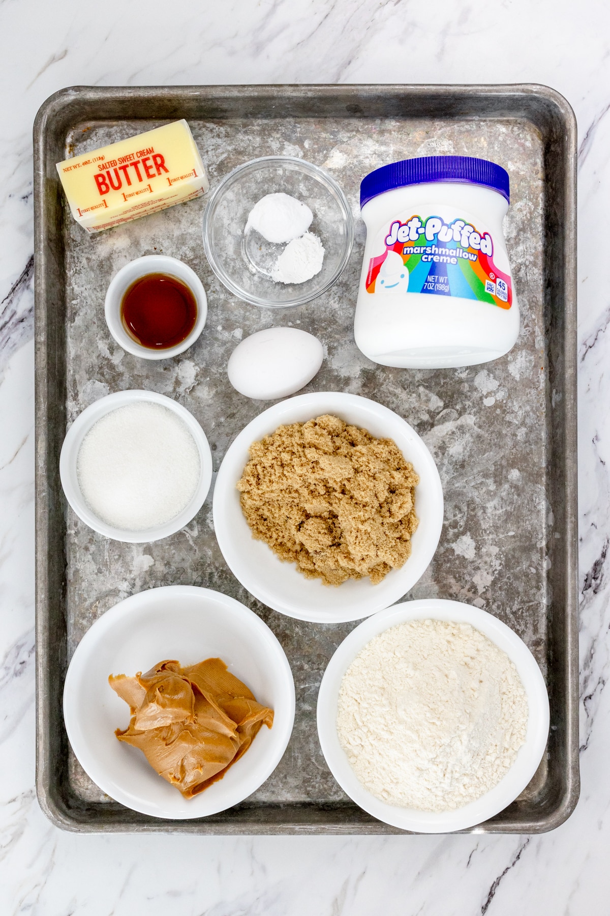 Top view of ingredients needed to make Fluffernutter Cookies in small bowls on a baking tray.