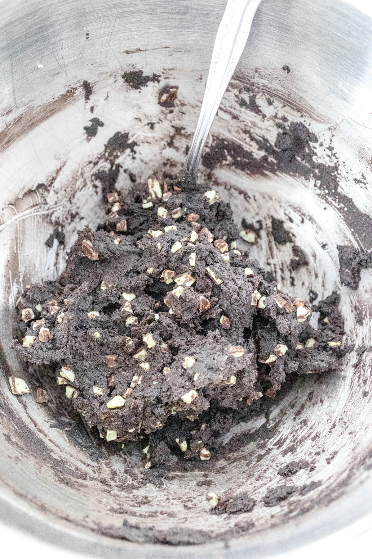 Close up of mixing bowl where Andes Mint Pieces have been stirred into the cookie dough by hand.
