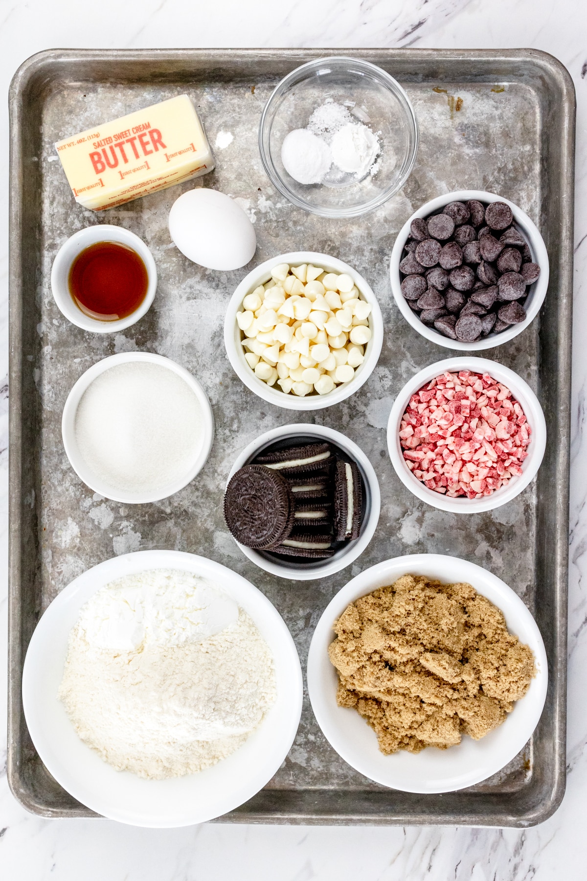 Top view of ingredients needed to make Peppermint Oreo Cookies in small bowls on a baking tray.