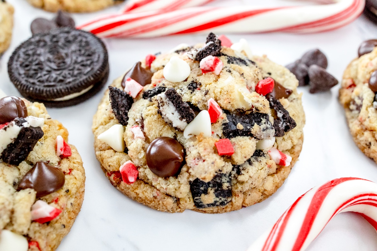 Close up of Peppermint Oreo Cookies on a white marble surface with chocolate chips, candy canes, and oreos around them.