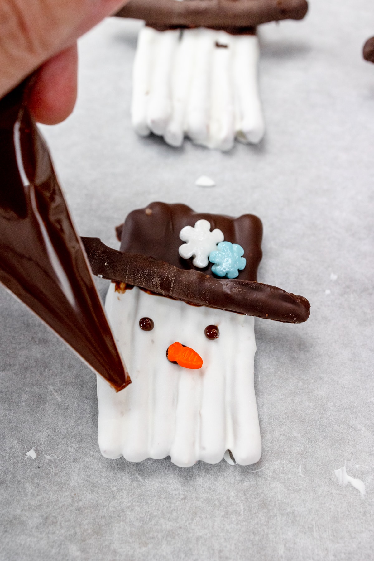Close up of snowman's chocolate features being piped onto it.