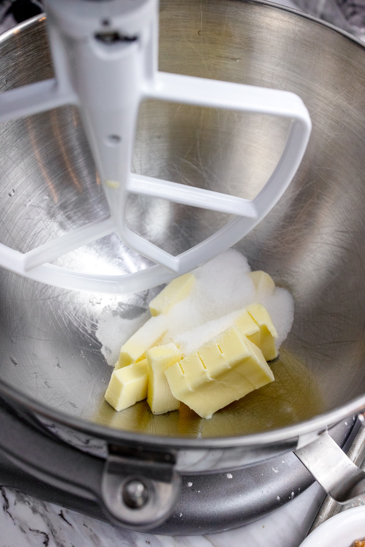 Close up of the bowl of a stand mixer with butter and brown sugar ready to be creamed together with a paddle attachment.