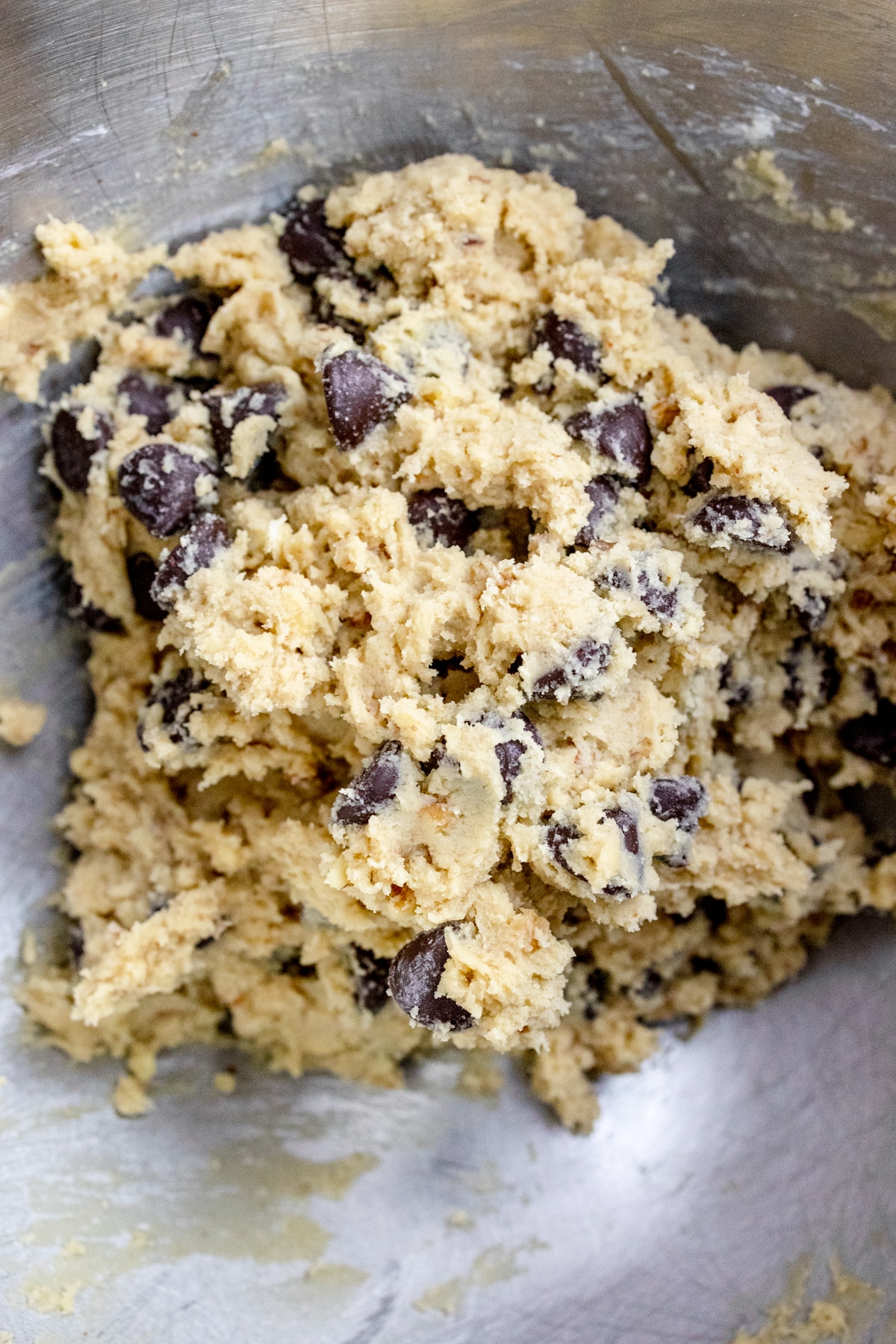 Close up of the bowl of a stand mixer with Chocolate Chip Walnut Cookie dough in it.