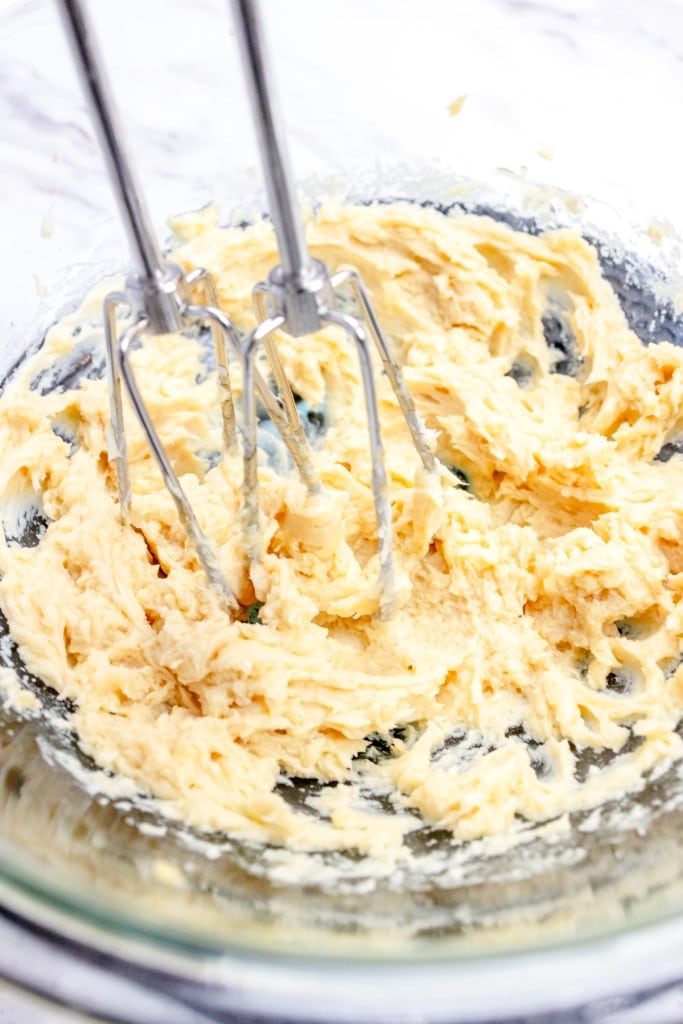 Close up of buttercream mixture being mixed with an electric mixer.