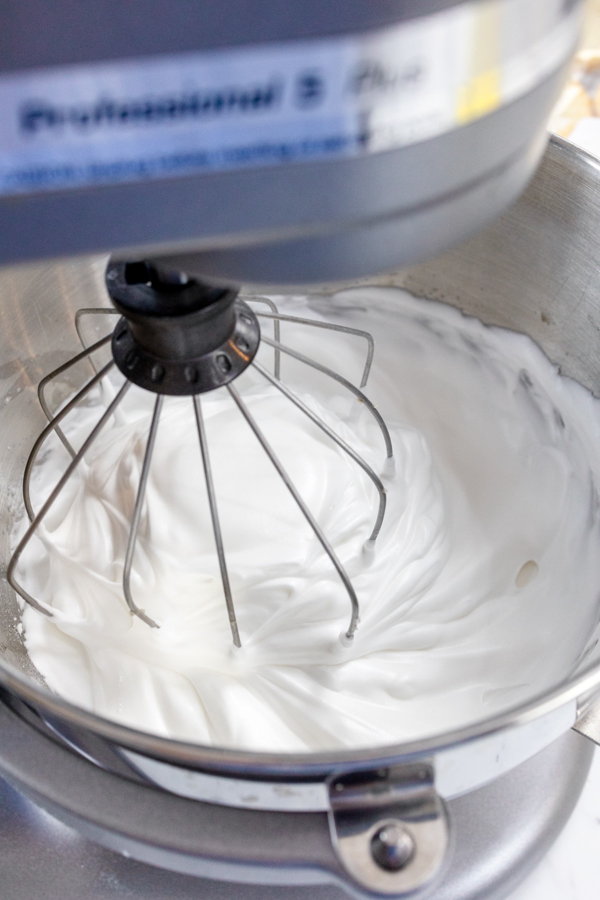 Close up view of meringue filling being whisked in a large mixing bowl.