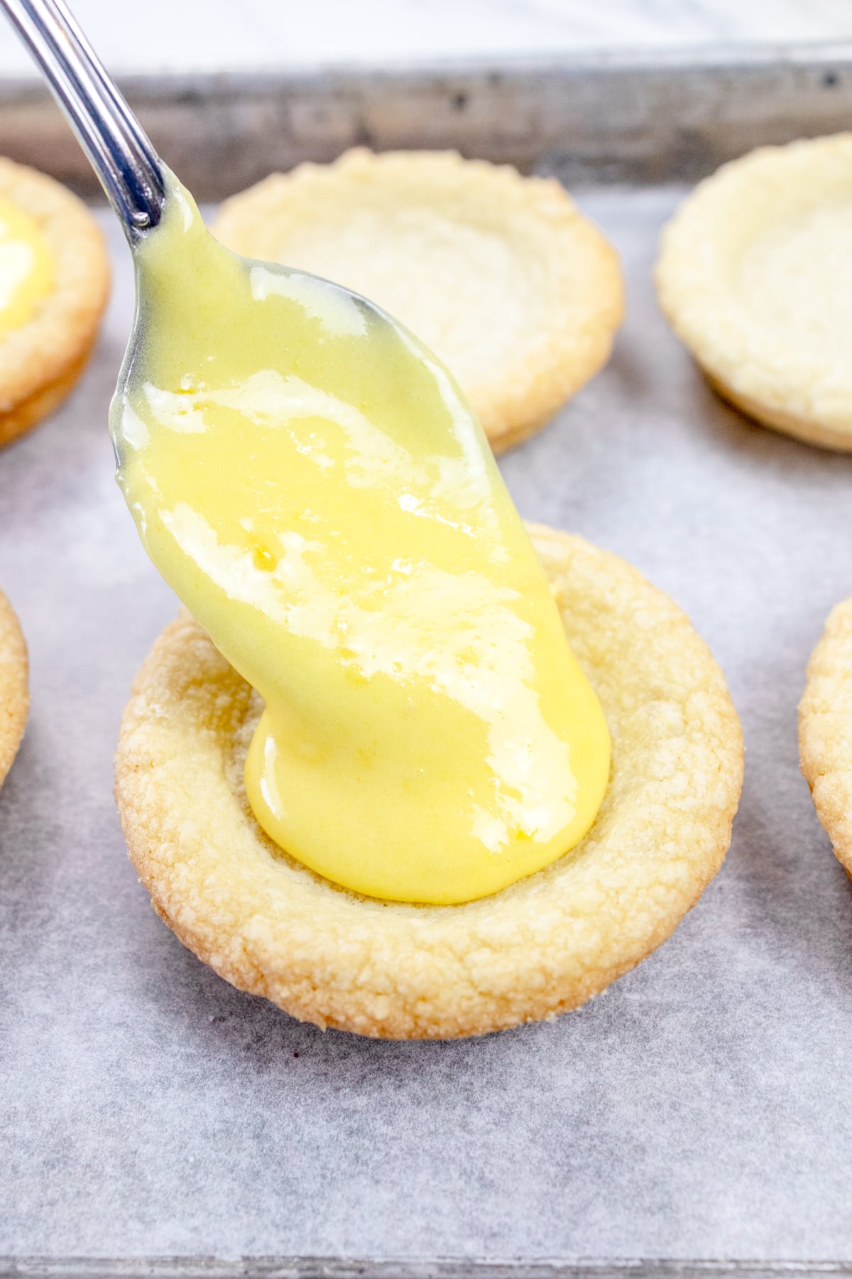 Close up view of a cookie being filled with lemon curd filling.