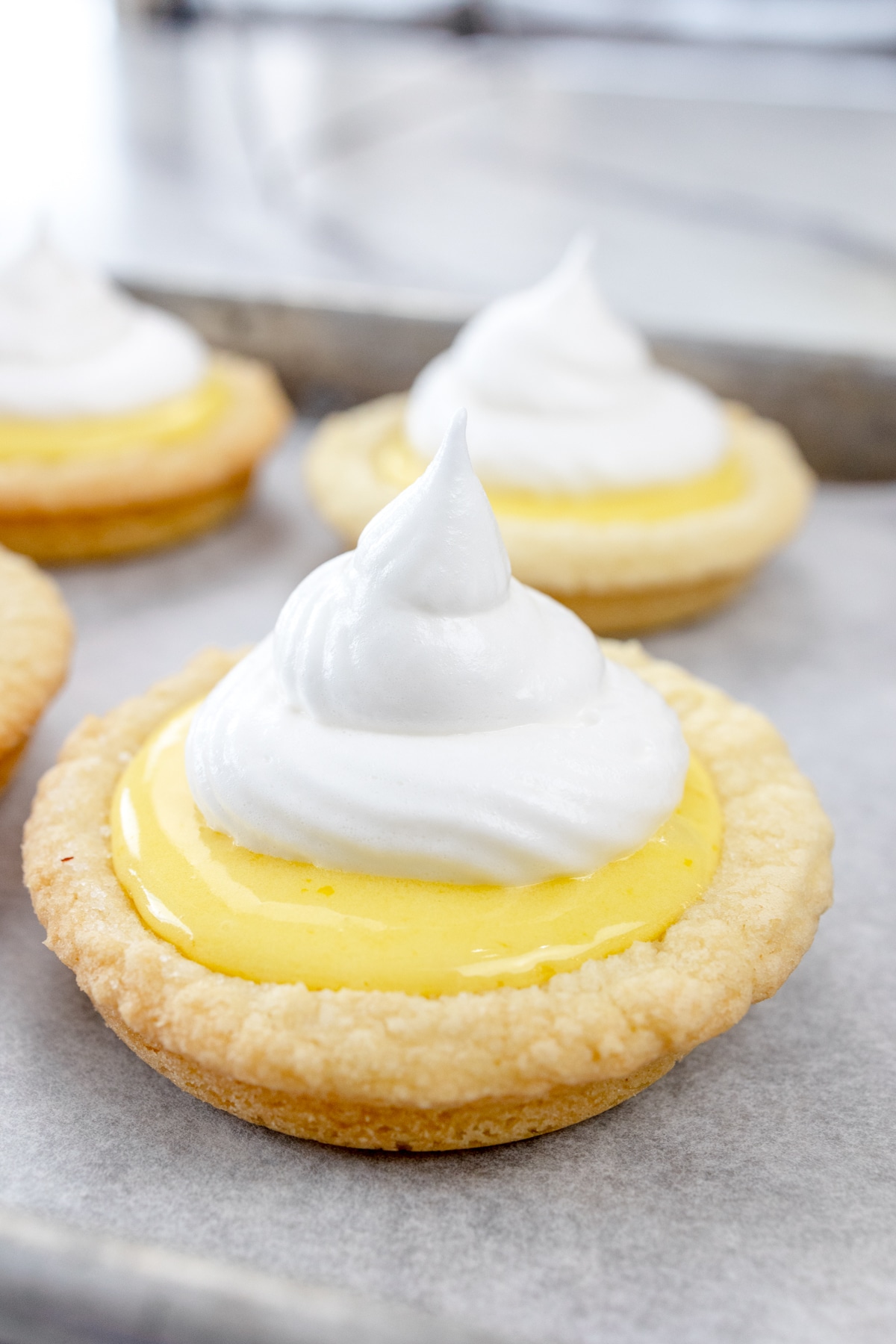 Close up view of lemon-filled cookies with the piped meringue topping.