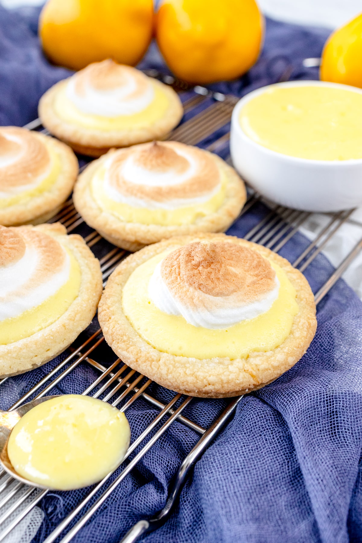 Close up view of Lemon Meringue Cookies on a wire rack, with a spoon filled with lemon curd next to them.