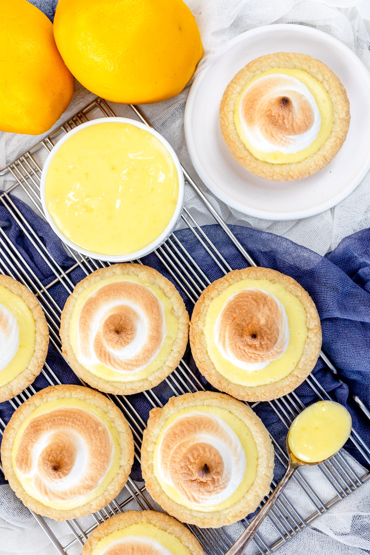 Top view of Lemon Meringue Cookies on a wire rack, with a spoon filled with lemon curd next to them.