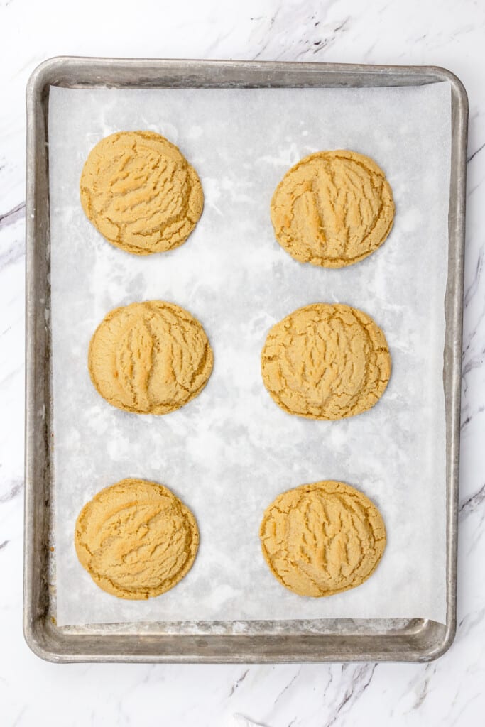 Top view of baking tray lined with parchment paper with freshly baked Brown Butter Sugar Cookies on it.