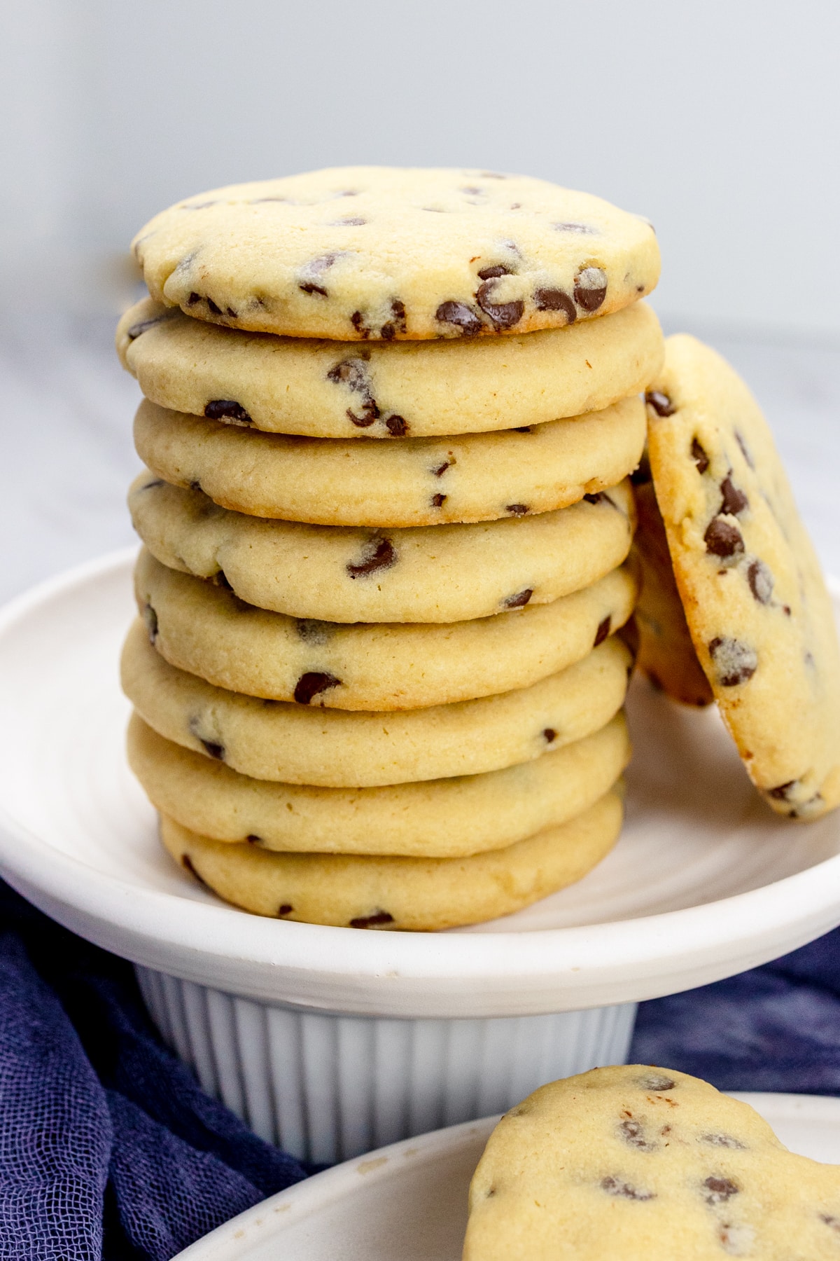 Close up of circular chocolate chip cookies in a stack on a plate.