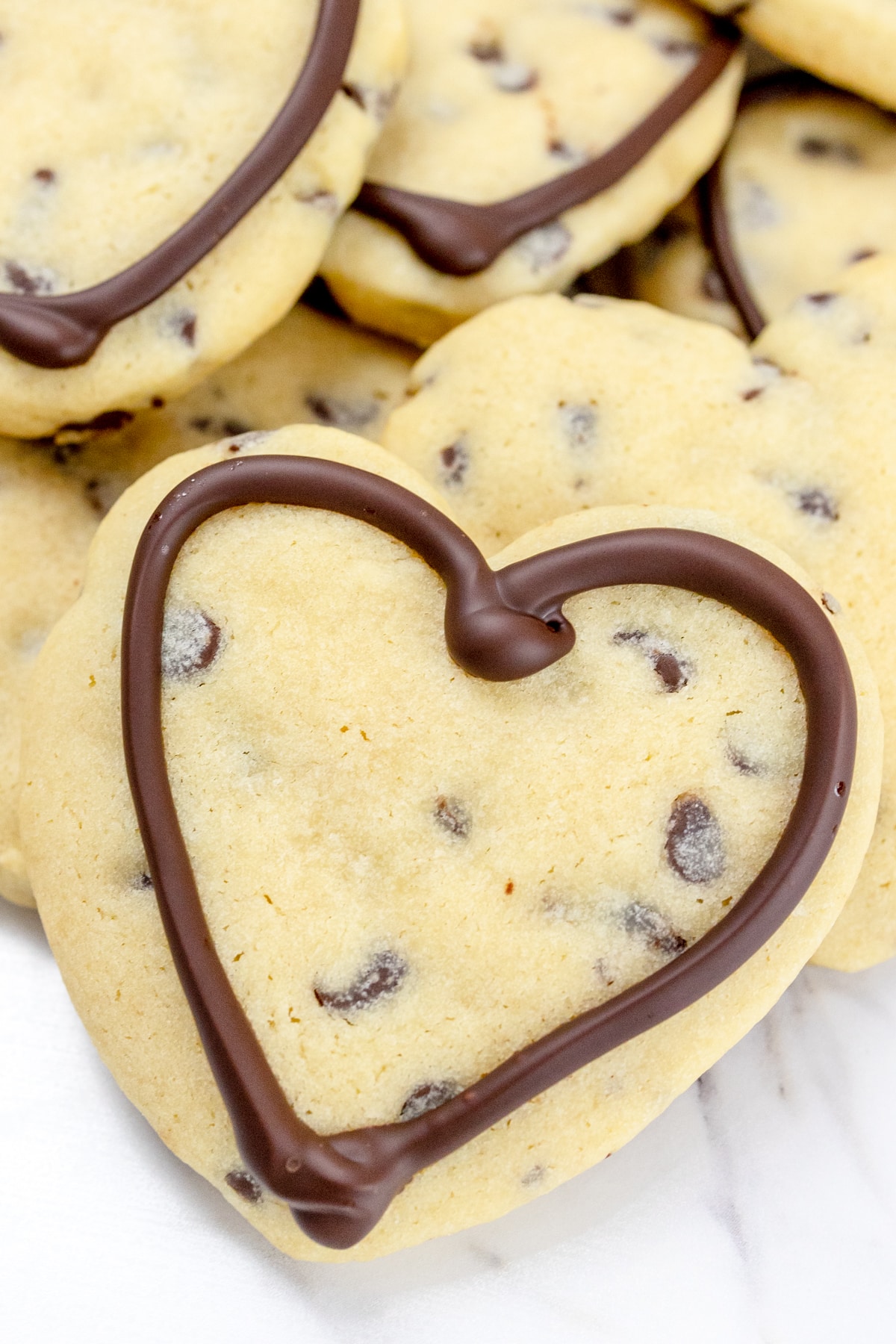 Top view of a chocolate chip cookies with melted chocolate hearts on them.