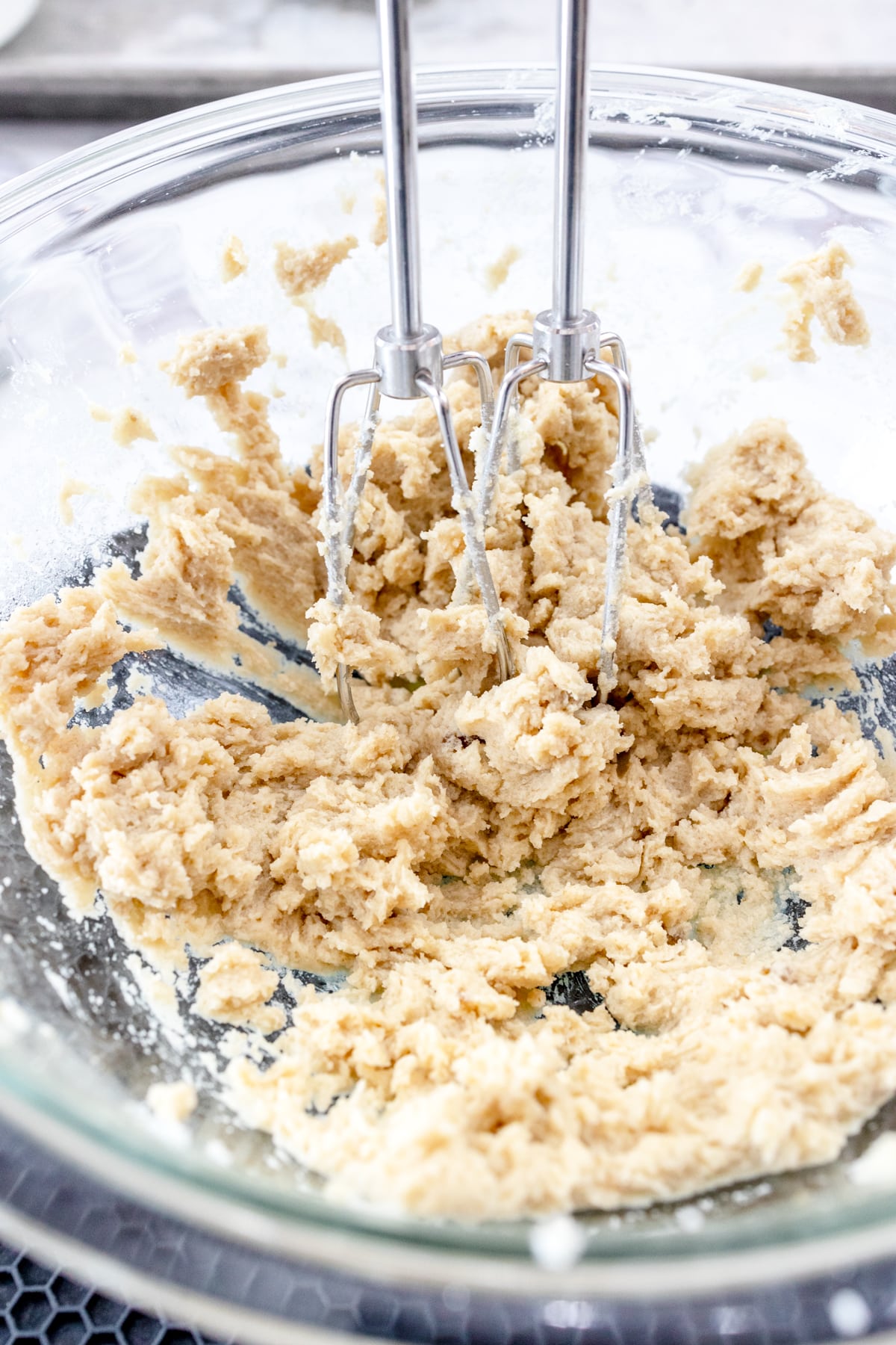 Close up view of butter and sugar mixture being creamed together with an electric hand mixer.