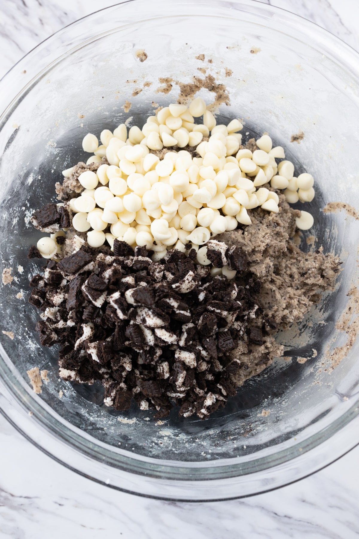 Top view of large mixing bowl with chopped oreos and white chocolate chips on top.