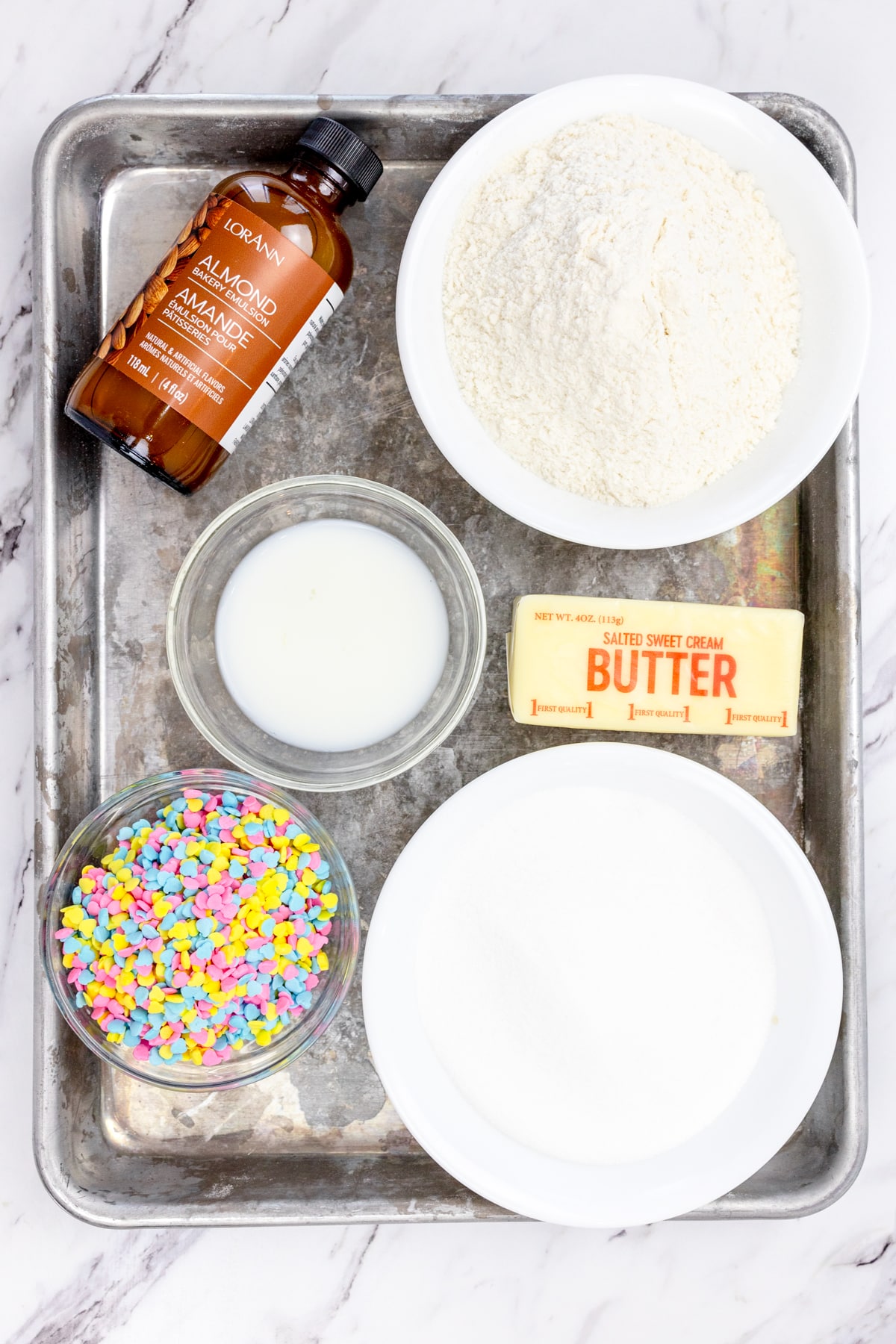 Top view of ingredients needed to make Edible Sugar Cookie Dough in small bowls on a baking tray.
