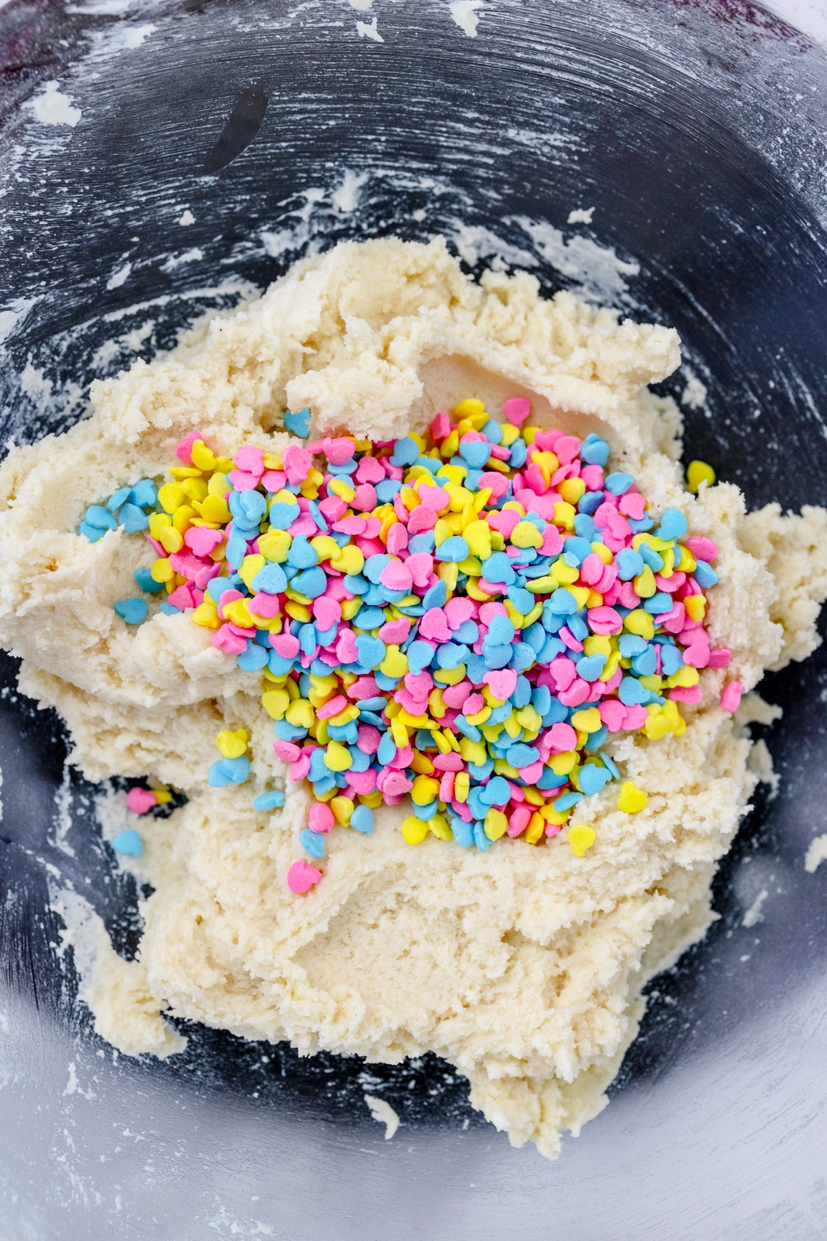 Close up of a mixing bowl with creamed mixture in it with sprinkles that have been added on top.