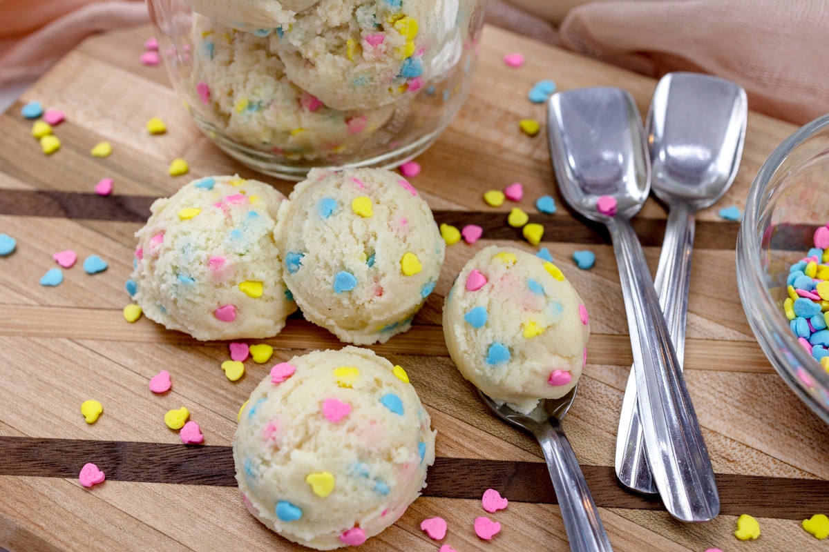 Scoops of edible sugar cookie dough with ice cream spoons.