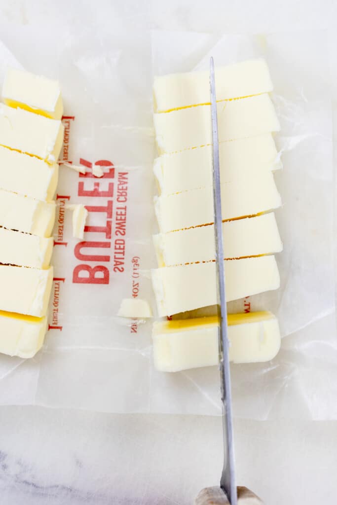 Top view of butter being sliced with a knife.