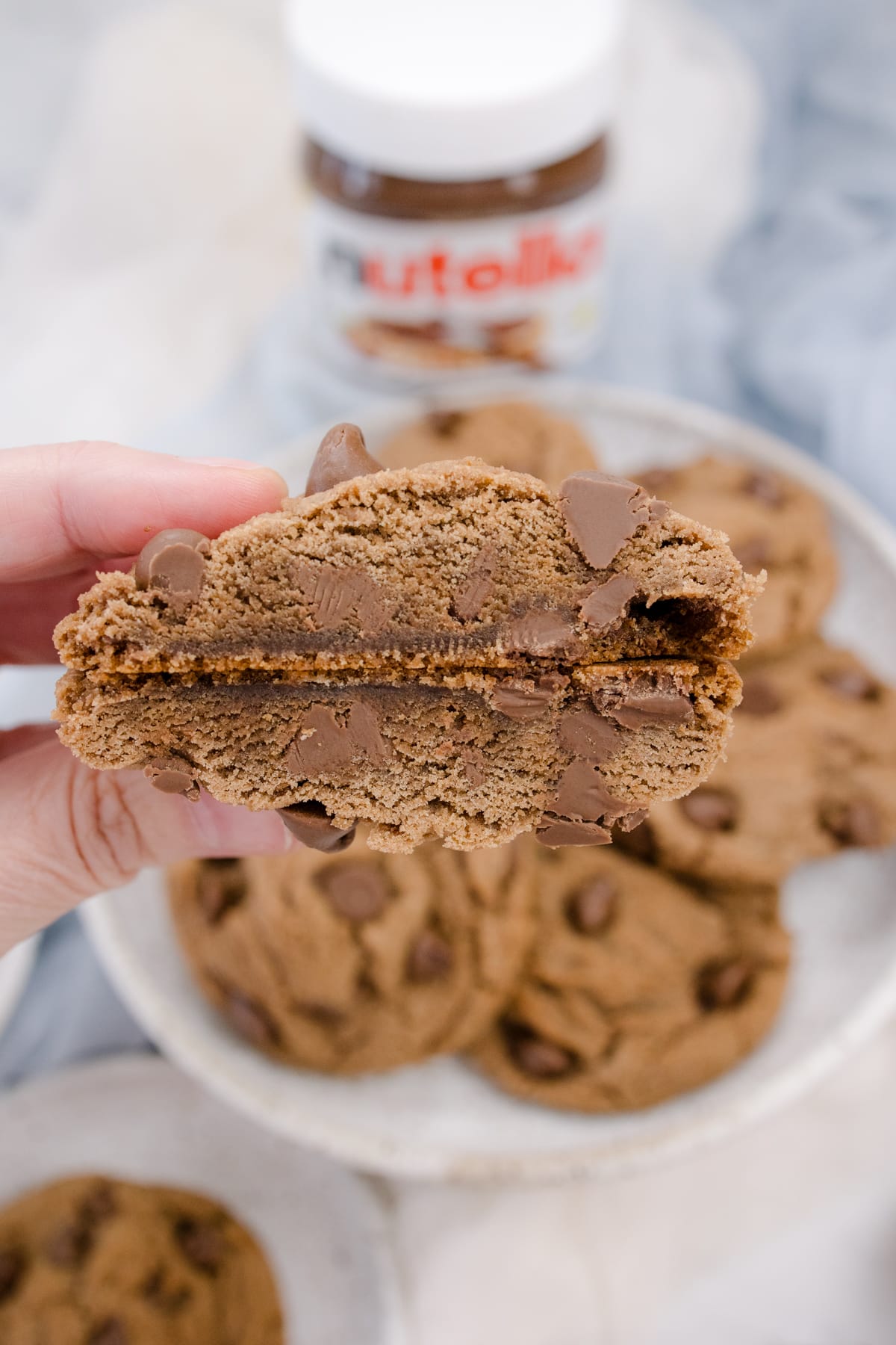 Close up of someone holding up a Nutella Cookie that has been sliced in half to reveal the middle.