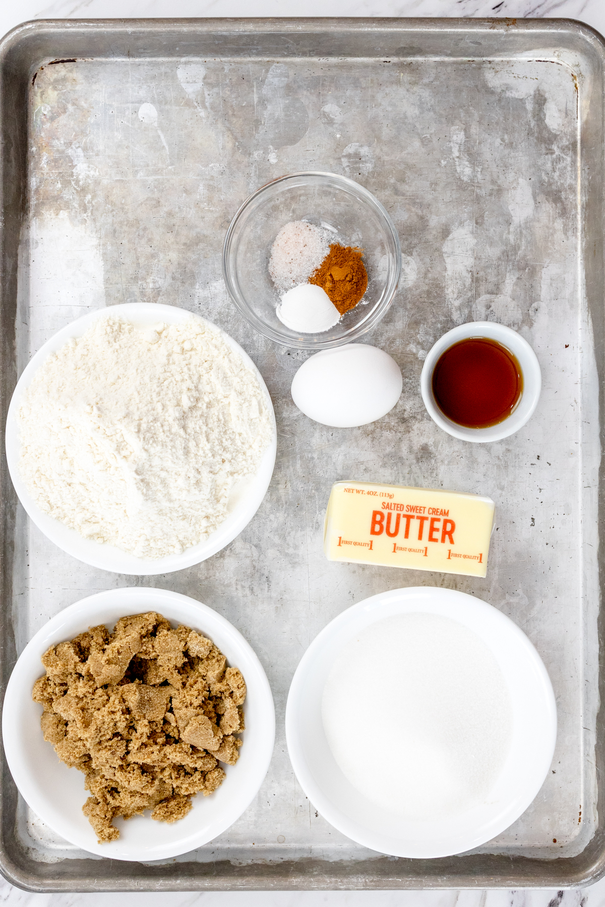 Top view of ingredients needed to make waffle cookies in small bowls on a baking tray.
