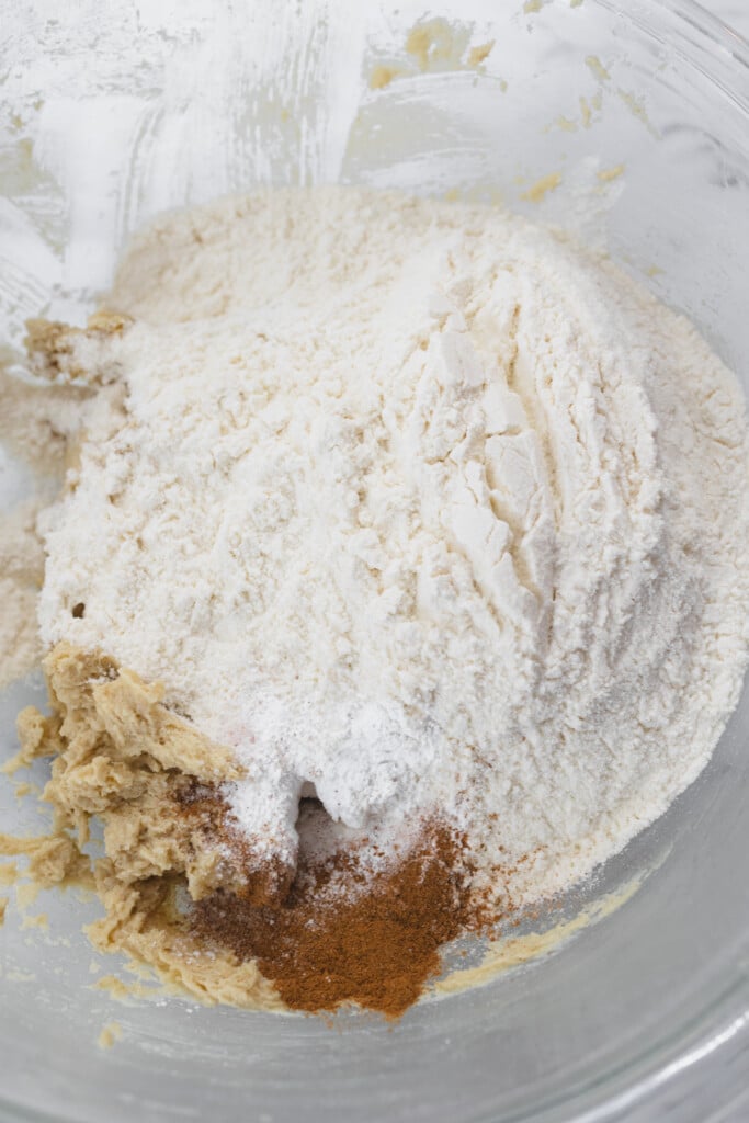 Top view of a glass mixing bowl with a creamed misture in the bottom and a flour mixture on top.