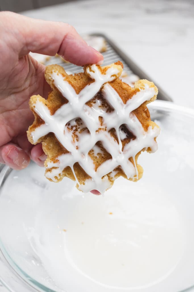 Top view of a waffle cookie being coated in powdered augar icing.