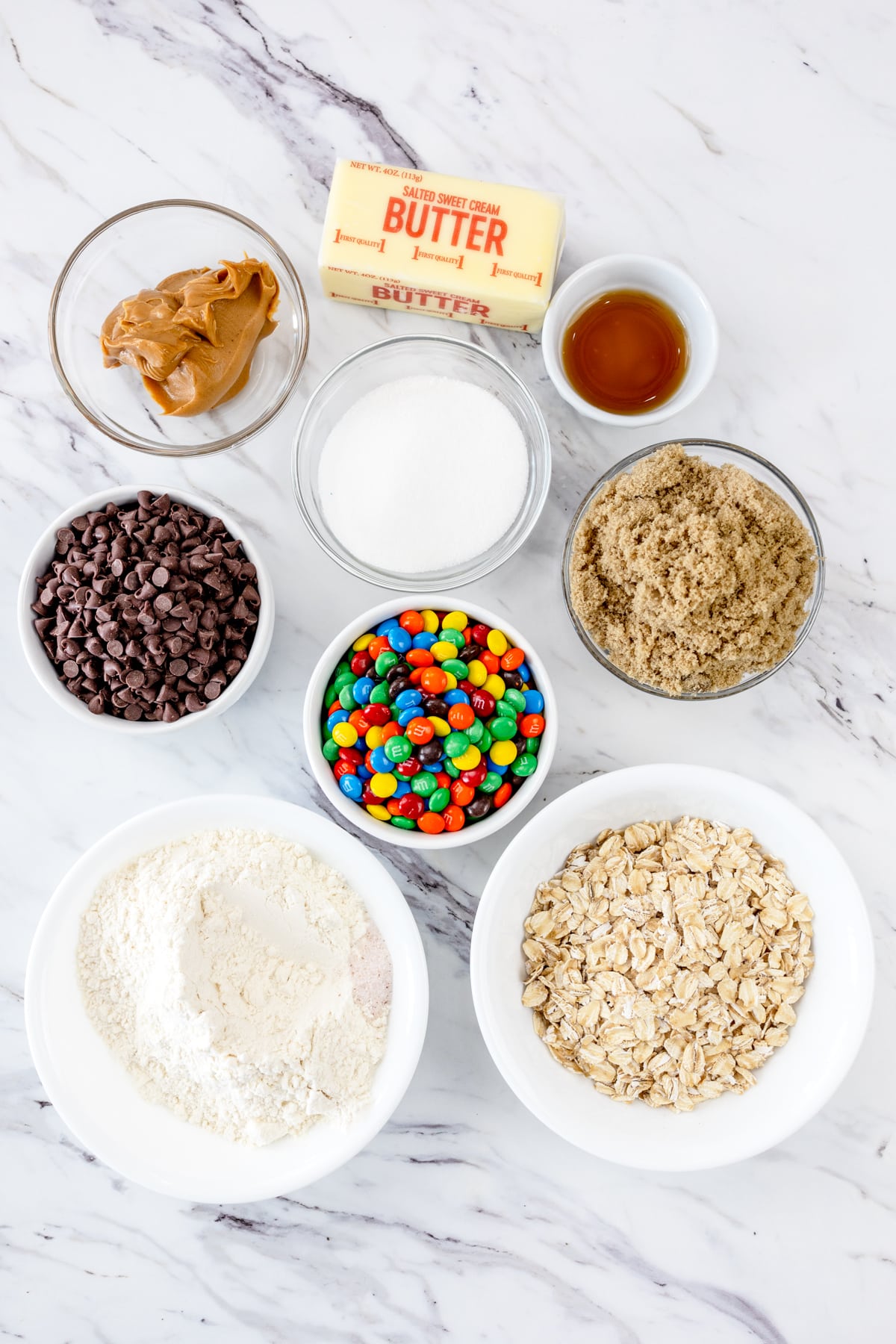 Top view of ingredients needed to make Monster Cookie Dough in small bowls on a baking tray.