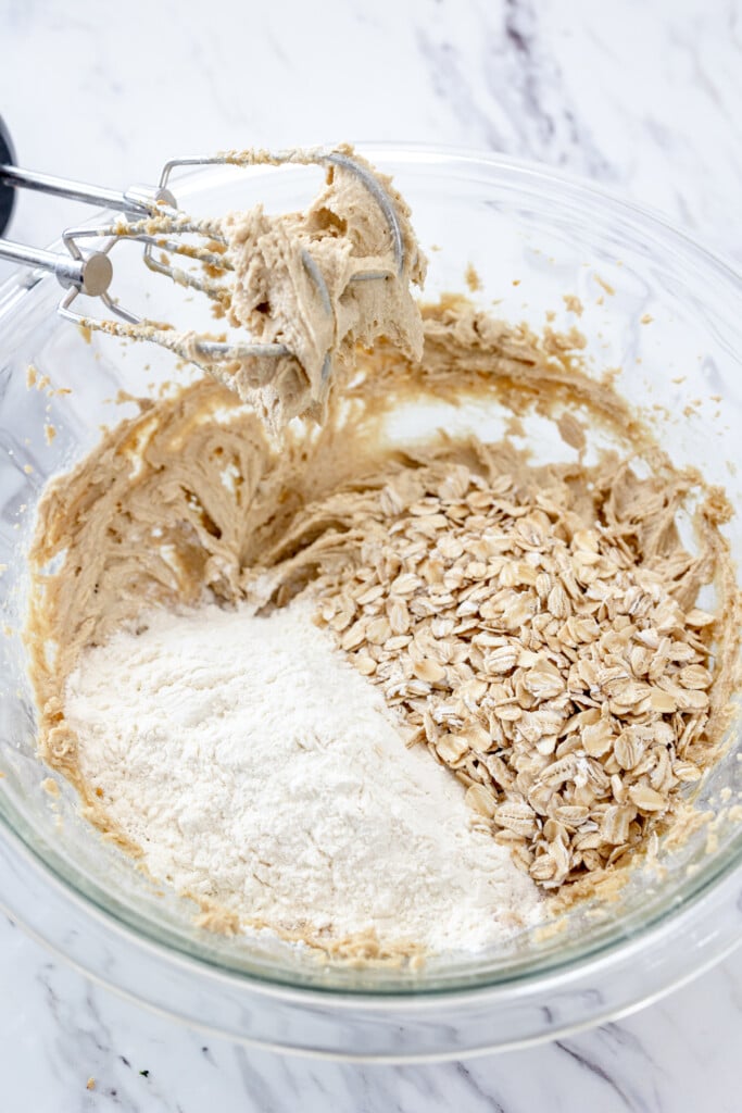 Close up view of a large mixing bowl with heat-treated flour and oats ready to be mixed into the peanut butter mixture.