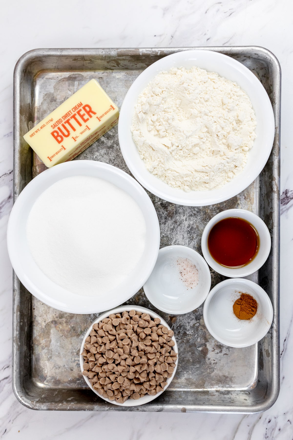 Top view of ingredients needed to make Edible Snickerdoodle Cookie Dough in small bowls on a baking tray.