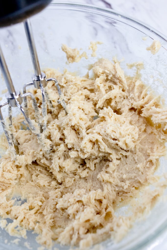 Close up of the bowl of a stand mixer with cookie dough in it.