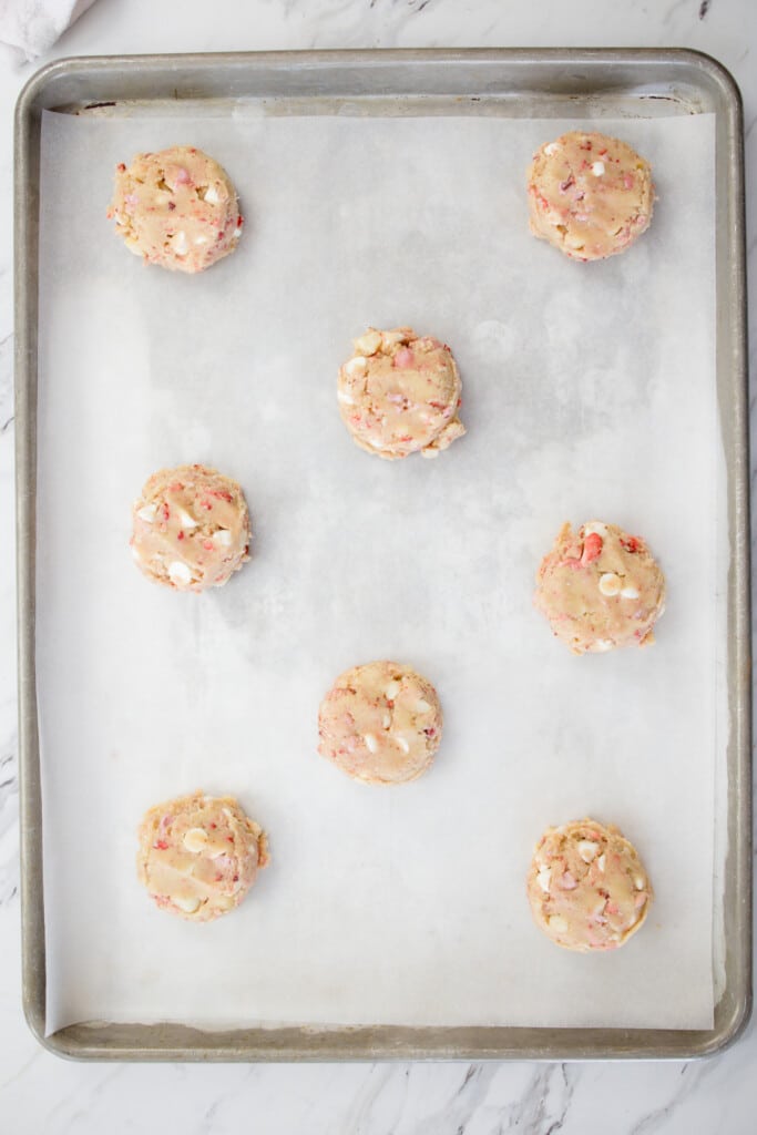 Top view of baking tray lined with parchment paper with freshly baked Cookies on it.