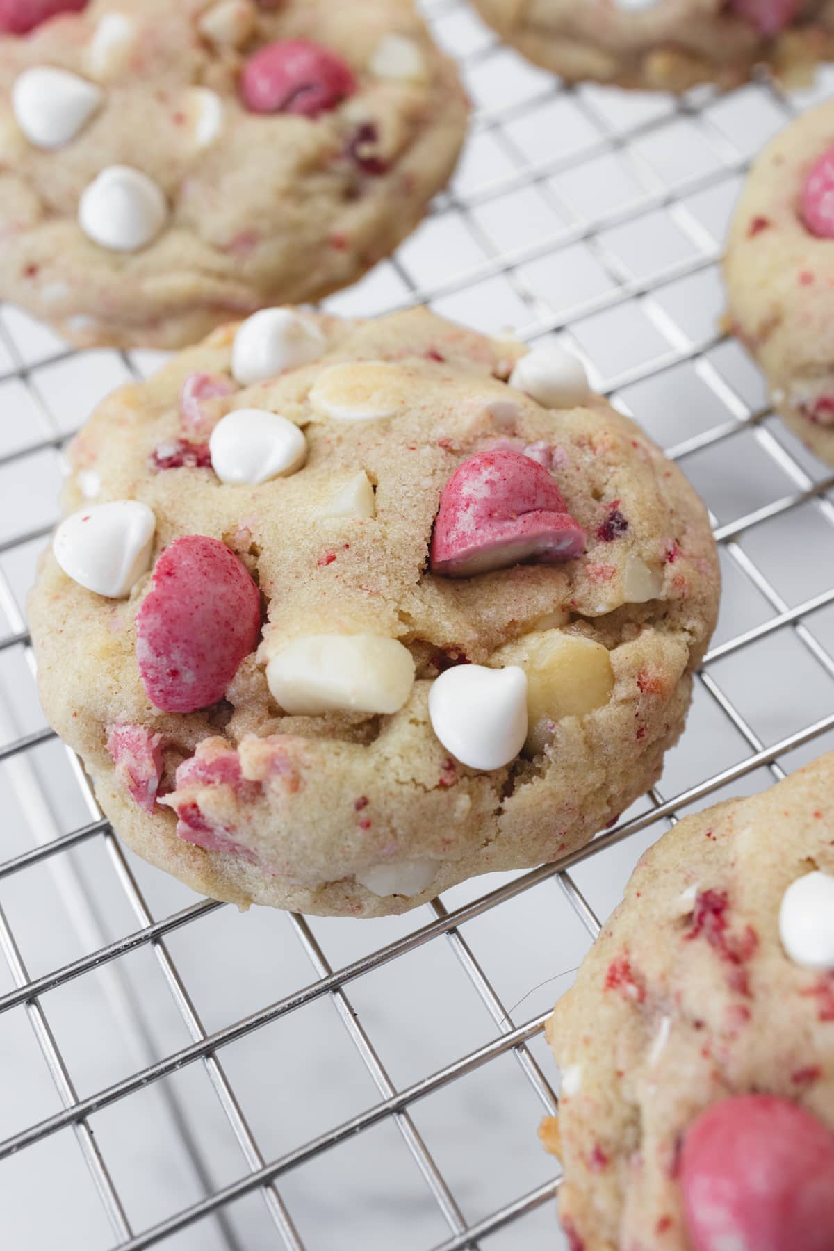 Close up view of Strawberry White Chocolate Macadamia Nut Cookies on a wire rack.