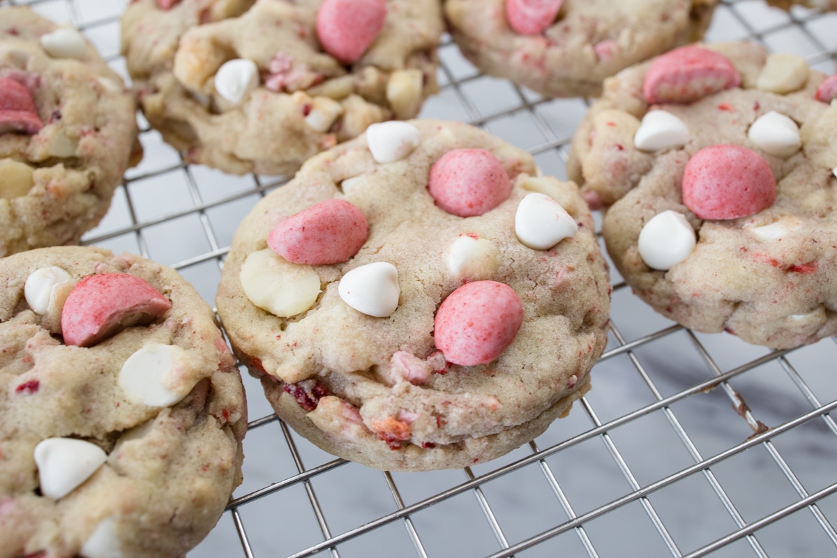 Close up view of Strawberry White Chocolate Macadamia Nut Cookies on a wire rack.