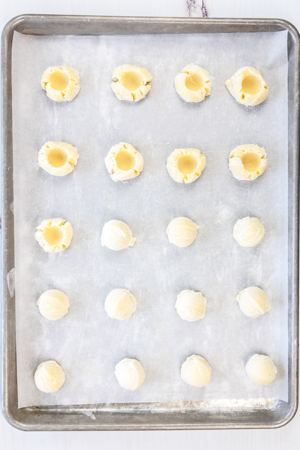 Overhead shot of a baking tray lined with parchment paper with cookie dough cups on it.