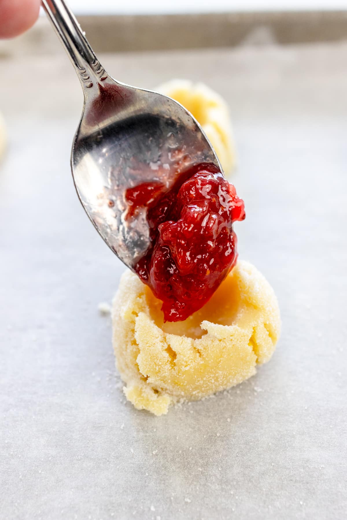 Close up image of a spoon filling a cookie dough cup with fig jam.