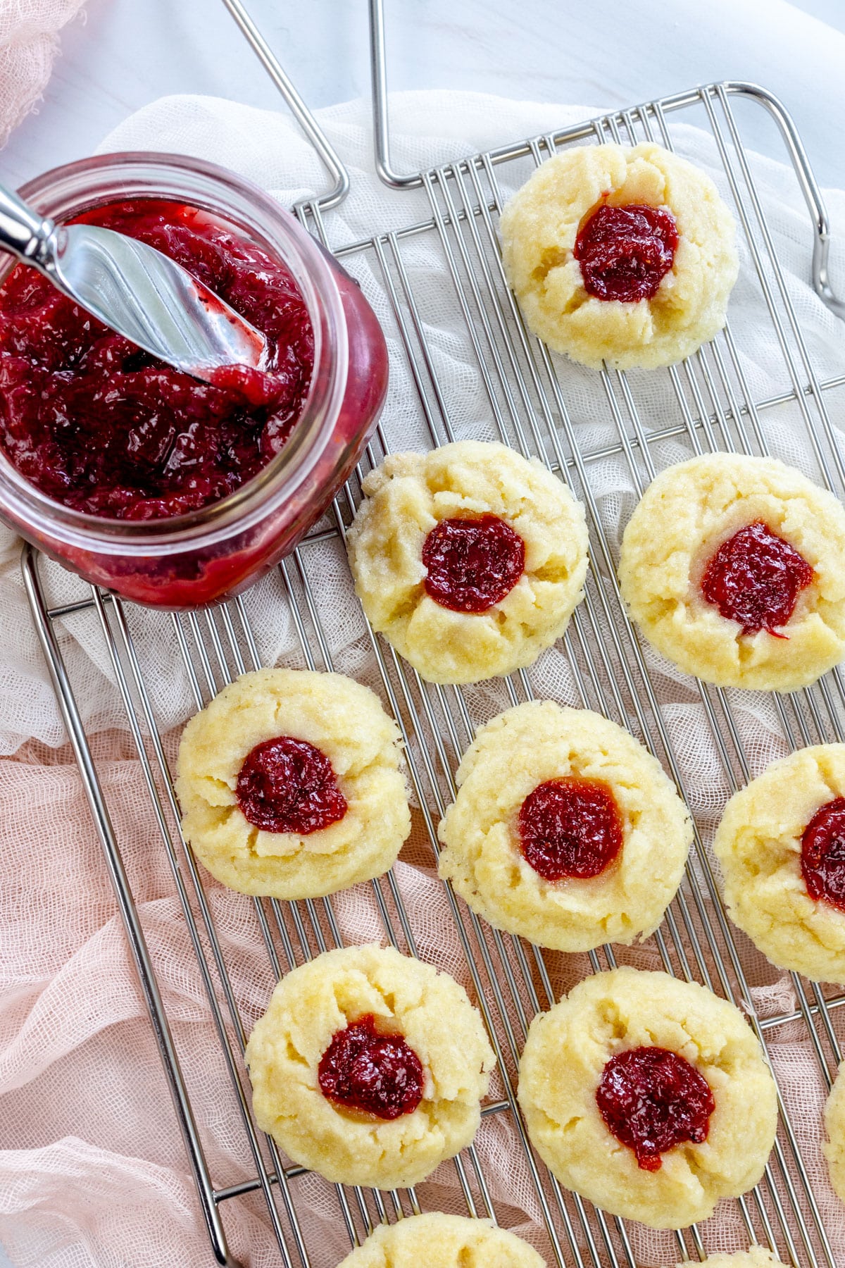 Overhead image of Fig Jam Cookies on a wire rack next to a jam jar with a knife in it.