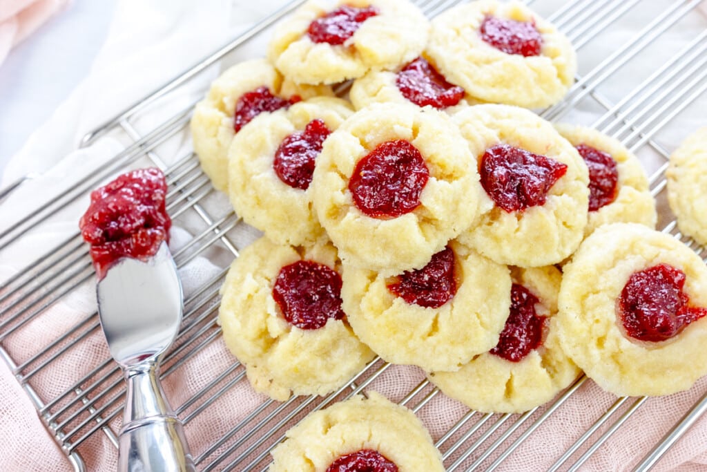 Overhead image of Fig Jam Cookies stacked on a wire rack next to a knife with jam on it.