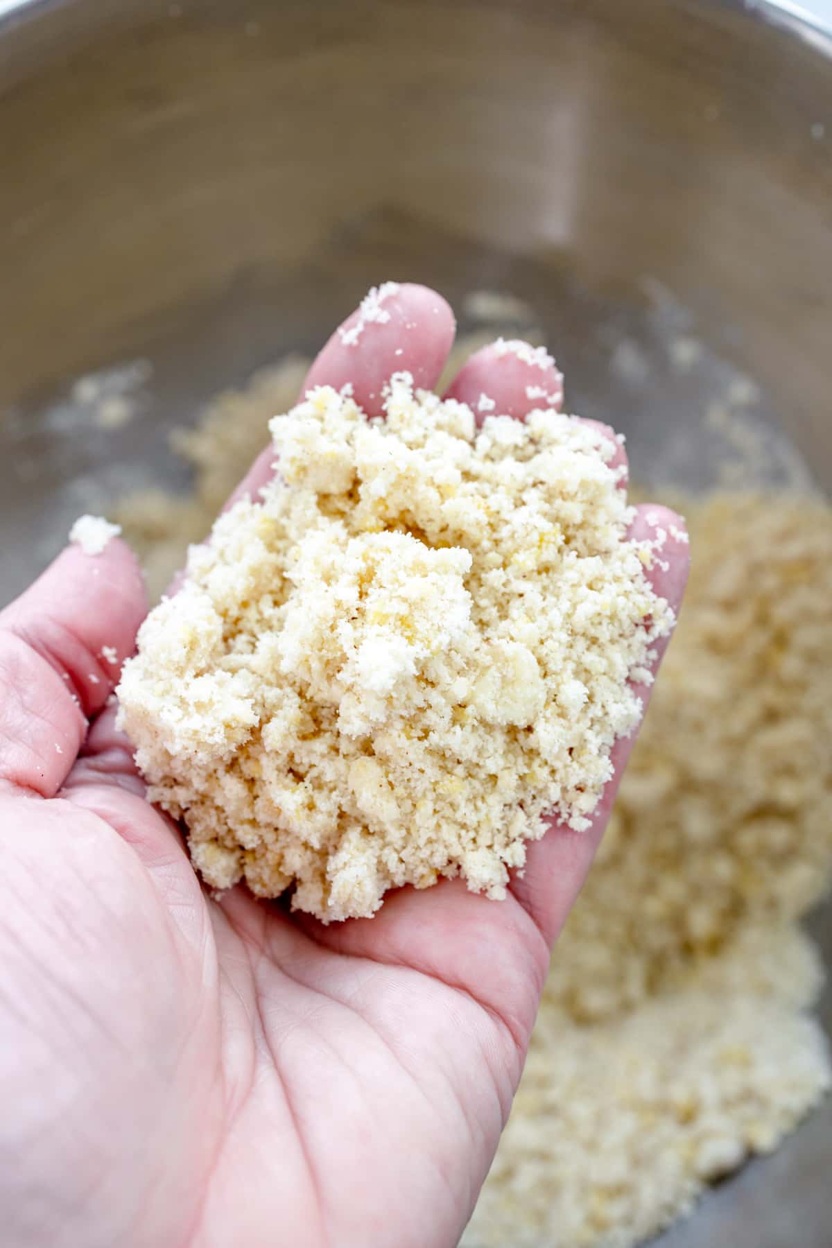 Close up image of a hand holding a handful of the pie crust mixture for Peach Pie Bars.