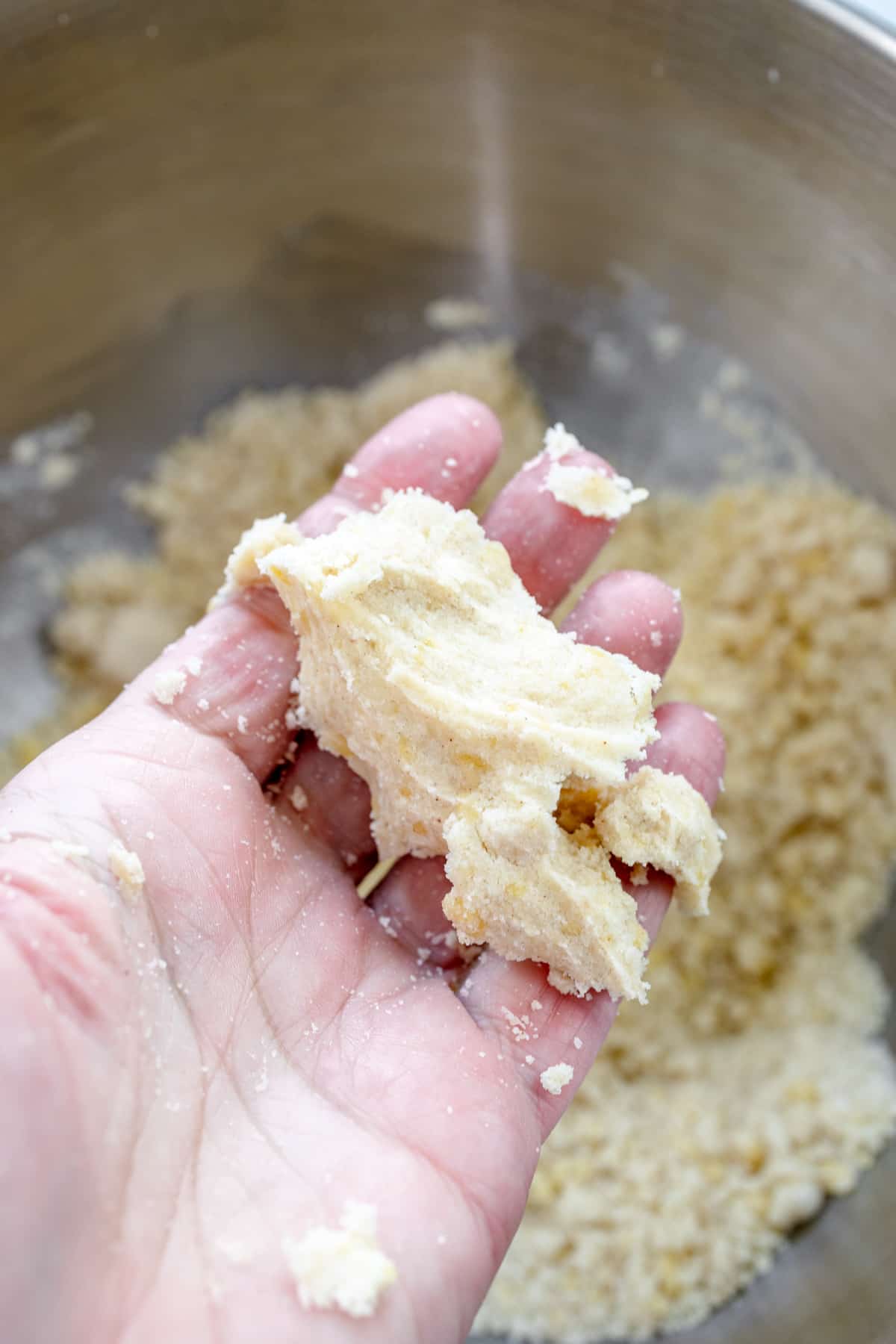 Close up image of a hand holding a handful of squeezed pie crust mixture for Peach Pie Bars.