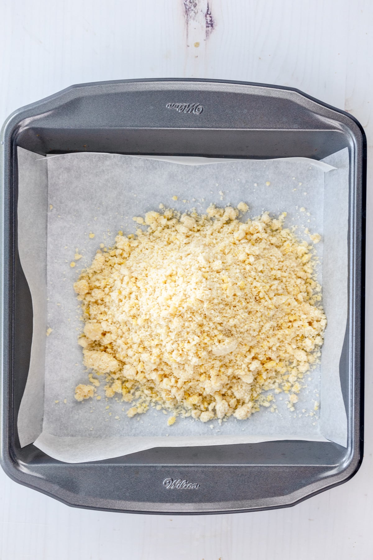 Overhead image of crust mixture for Peach Pie Bars added to the dish.