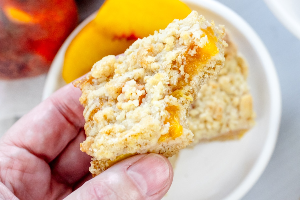 Close up image of a hand holding a Peach Pie Bar.