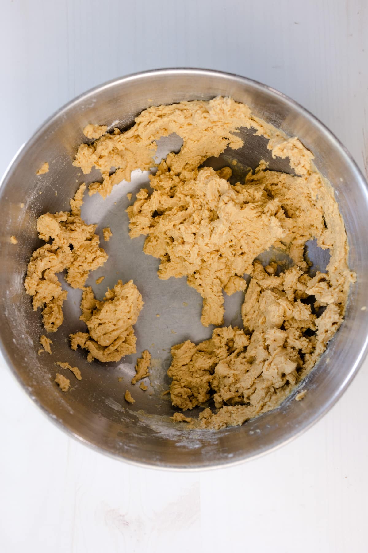 Overhead shot of a mixing bowl with Peanut Butter, Powdered Sugar, and Vanilla Extract being combined.