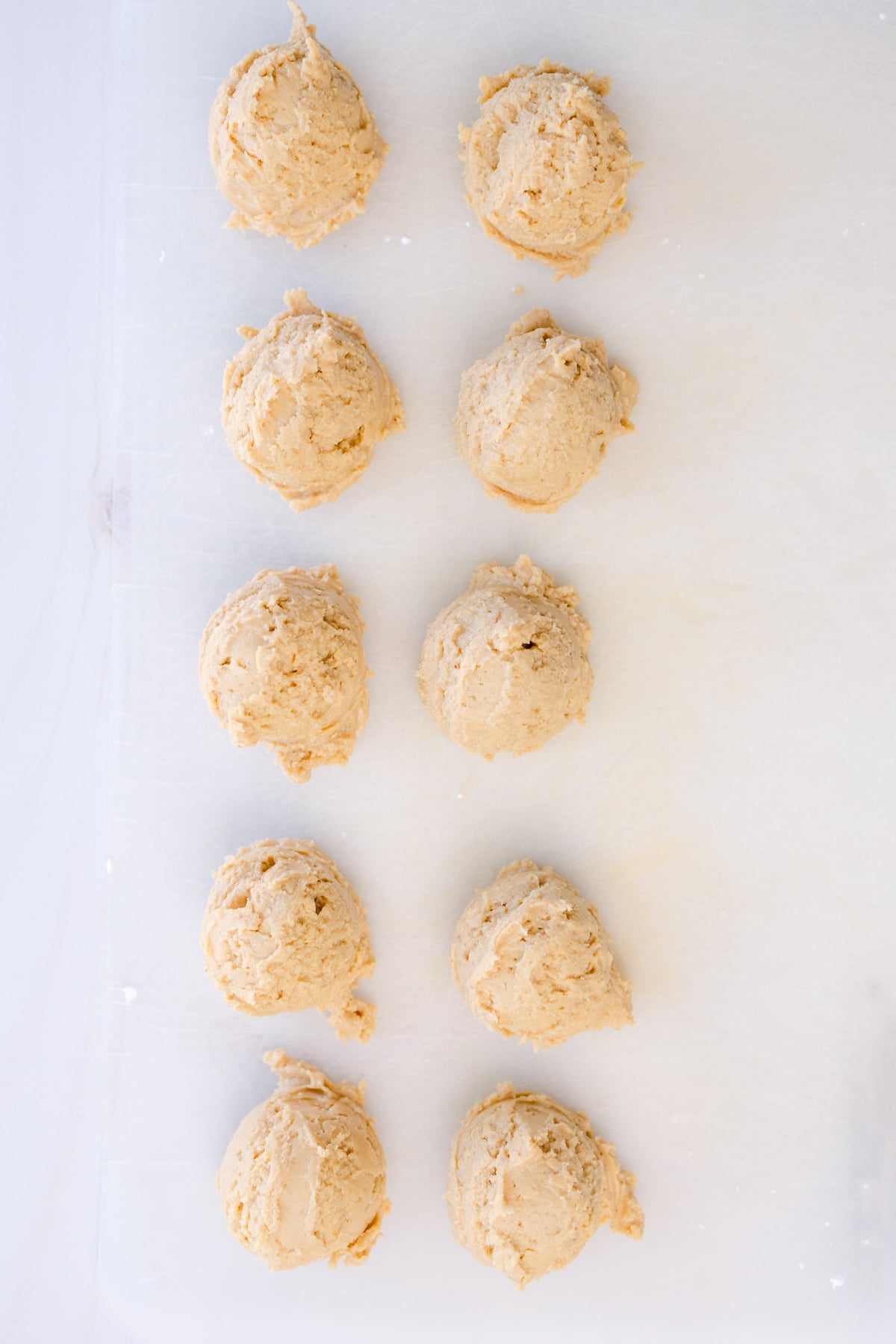 Overhead shot of peanut butter balls on a baking tray lined with parchment paper.