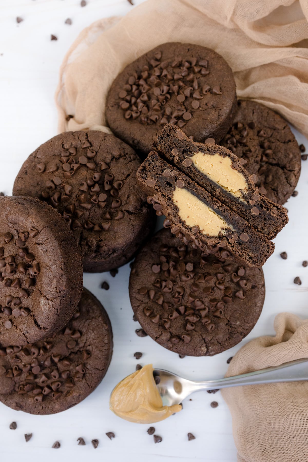 Overhead shot of Peanut Butter Stuffed Chocolate Cookies on a white surface, and one is cut open to reveal the middle.